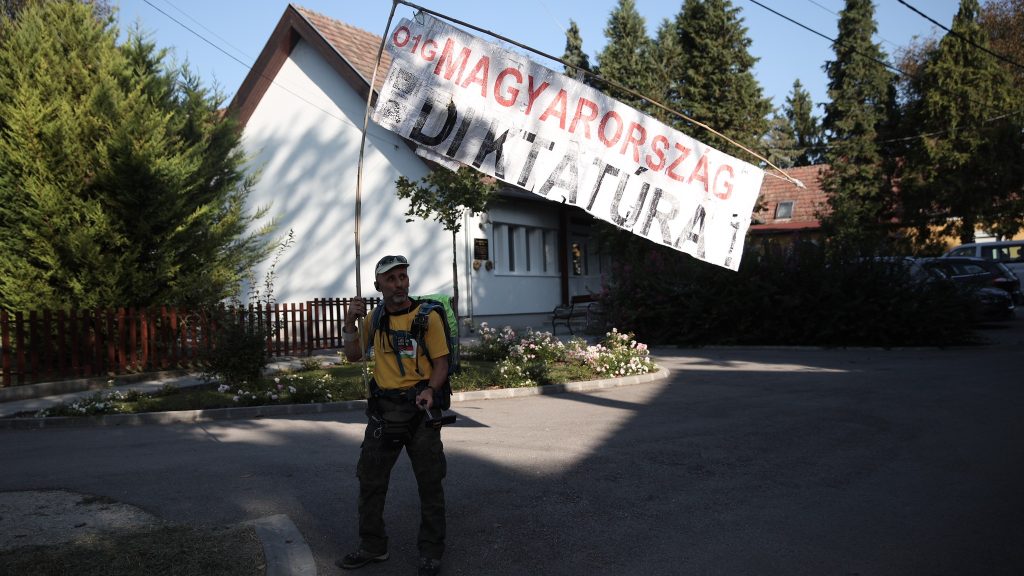 Tüntető civilek transzparensekkel várják Orbán Viktort Kötcsén