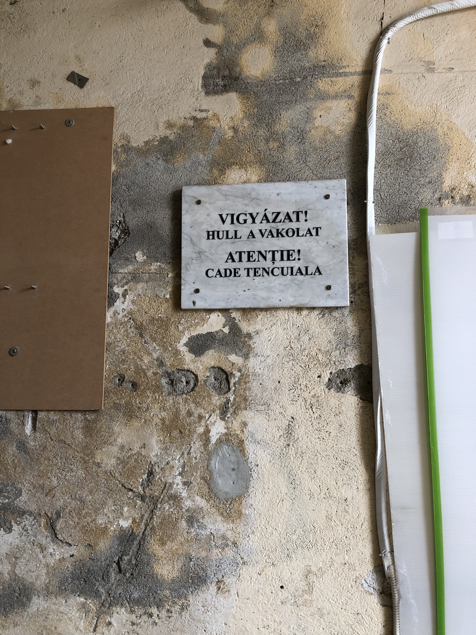 Szürreál: Emléktáblának tűnő felirat figyelmeztet a vakolathullásra Sepsiszentgyörgyön 1