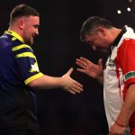 Luke Littler (balra) és Mensur Suljovic kezet ráznak, miután előbbi nyert a dartsvilágbajnokságon, Londonban.