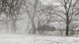 autó téli tájban, hófúvás közben