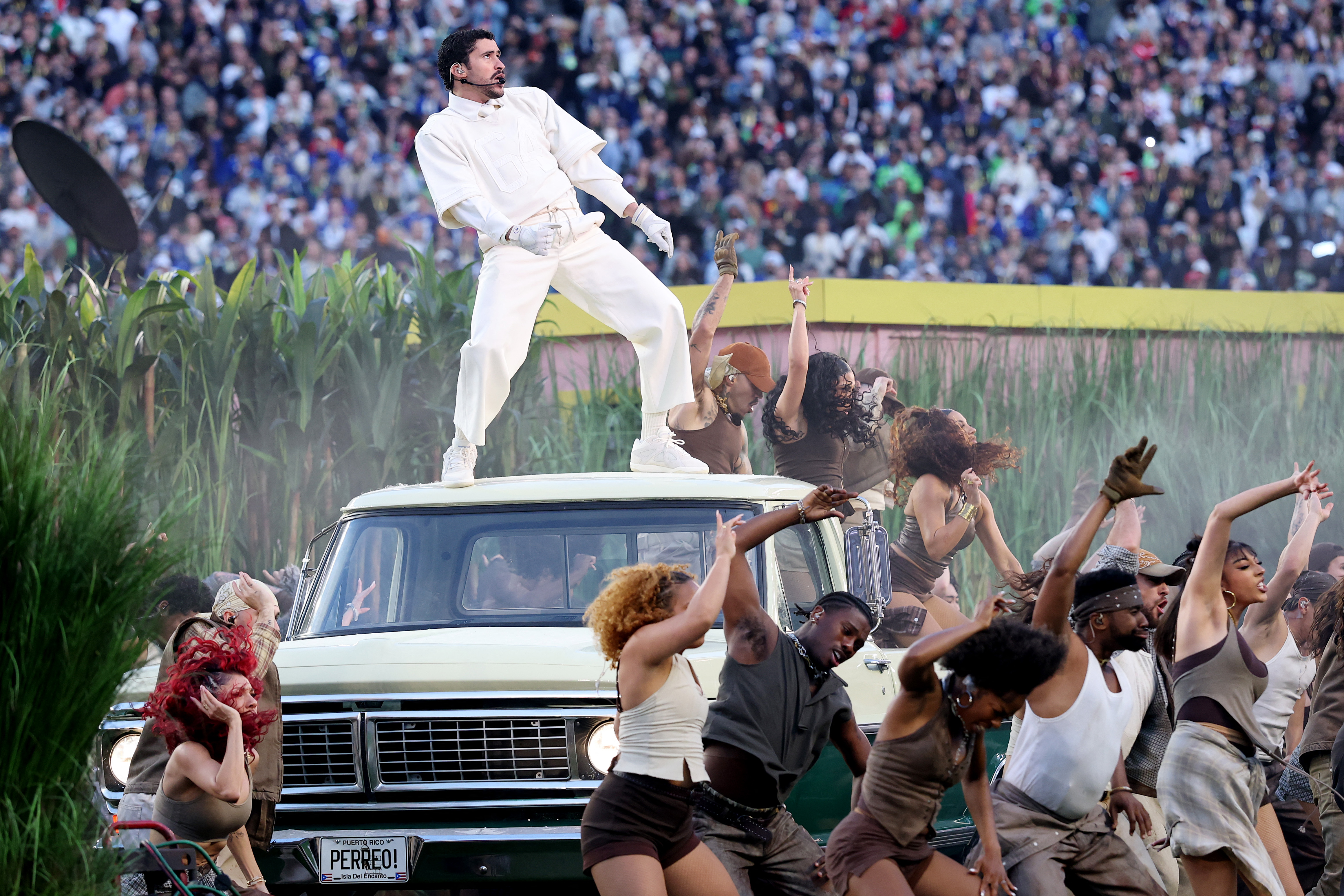 Bad Bunny egy fehér autó tetején énekel a 2026-os Super Bowl színpadán