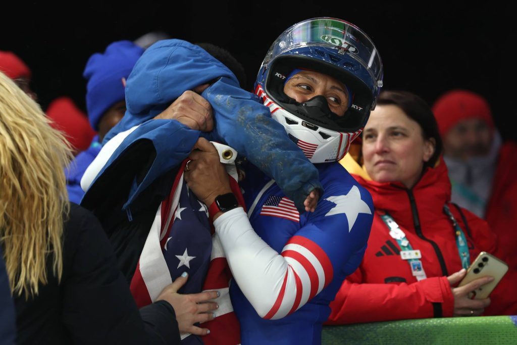 CORTINA D'AMPEZZO, ITALY - FEBRUARY 16: Gold medalist Elana Meyers Taylor of Team United States celebrates with a member of her family after winning the Women's Monobob Bobsleigh Heat 4 on day ten of the Milano Cortina 2026 Winter Olympic games at Cortina Sliding Centre on February 16, 2026 in Cortina d'Ampezzo, Italy. (Photo by Julian Finney/Getty Images)
