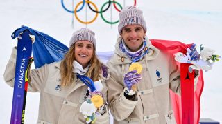 Gold medallists France's Thibault Anselmet (R) and France's Emily Harrop celebrate on the podium after competing in the mixed relay ski mountaineering event during the Milano Cortina 2026 Winter Olympic Games at the Stelvio Ski Centre in Bormio (Valtellina) on February 21, 2026.