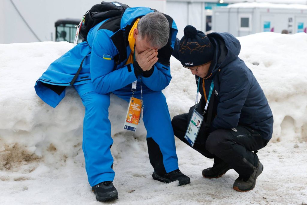 Mykhailo Heraskevych (L), the father of Ukraine's Vladyslav Heraskevych, reacts after his son was disqualified from the Milano Cortina 2026 Winter Olympic Games in Cortina d'Ampezzo on February 12, 2026. Ukrainian skeleton racer Vladyslav Heraskevych was disqualified from the Winter Olympics on February 12, 2026 after refusing to back down over his banned helmet, which depicts victims of his country's war with Russia. In a statement, the International Olympic Committee said Heraskevych is "not allowed to participate at Milano-Cortina 2026 after refusing to adhere to the IOC athlete expression guidelines". 