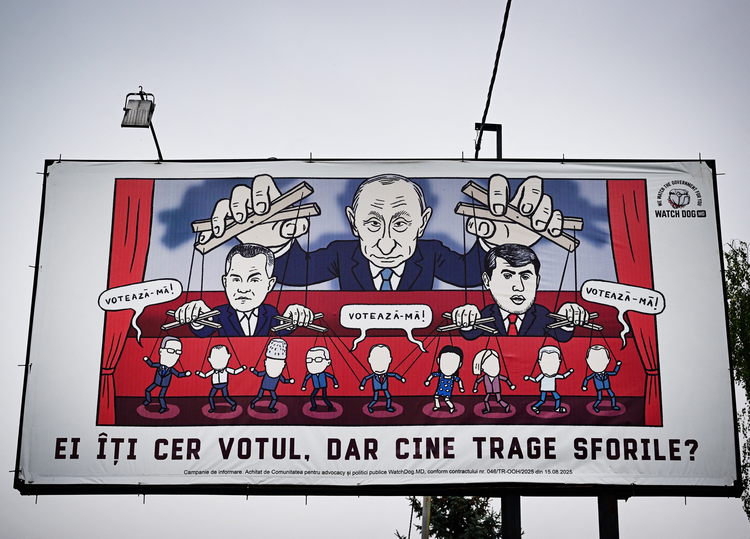 Karikatúra egy óriásplakáton, amelyen Vlagyimir Putyin a szökésben lévő Ilan Shor és Vladimir Plahotniuc bábjait mozgatja Ungheni városában Moldovában 2025. szeptember 24-én.