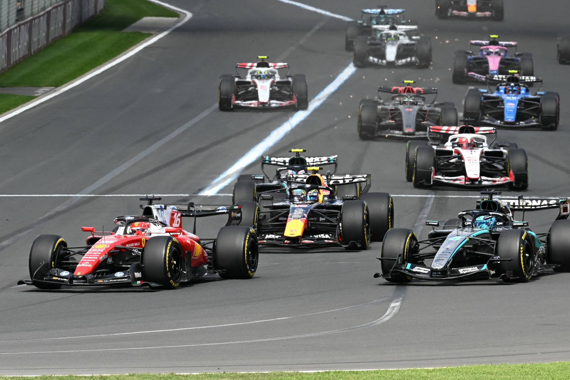 Ferrari's Monegasque driver Charles Leclerc (L) drives next to Mercedes' British driver George Russell (R) at the start of the Formula One Australian Grand Prix at the Albert Park Circuit in Melbourne on March 8, 2026.