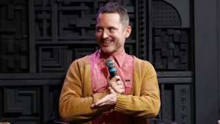 Elijah Wood mikrofonnal a kezében mosolyog a Cinema Cafe: Visitations podcast élő felvételén