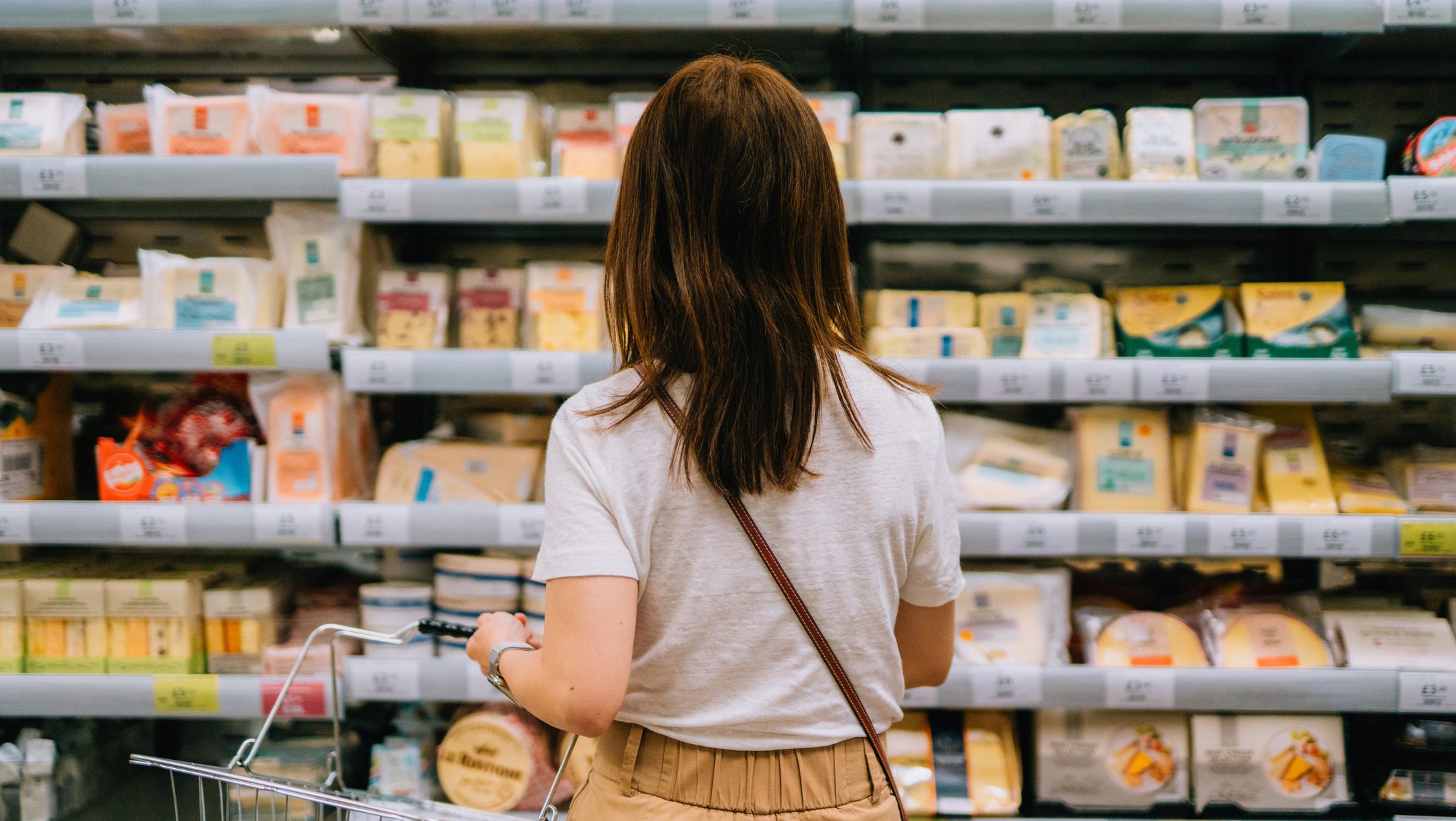 Young woman choosing dairy products from the refrigerator in supermarket. Healthy eating and lifestyle.