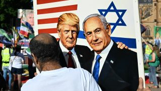 A member of the Iranian community in Australia holds a placard in support of US President Donald Trump and Israeli Prime Minister Benjamin Netanyahu during a rally following US and Israeli attacks on Iran sparking the Middle East war, in Sydney on March 14, 2026. (Photo by Saeed KHAN / AFP)