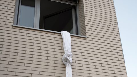 Ablakon kilógó összecsomózott lepedők