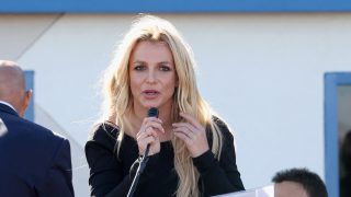 Britney Spears mikrofonba beszél egy színpadon.
