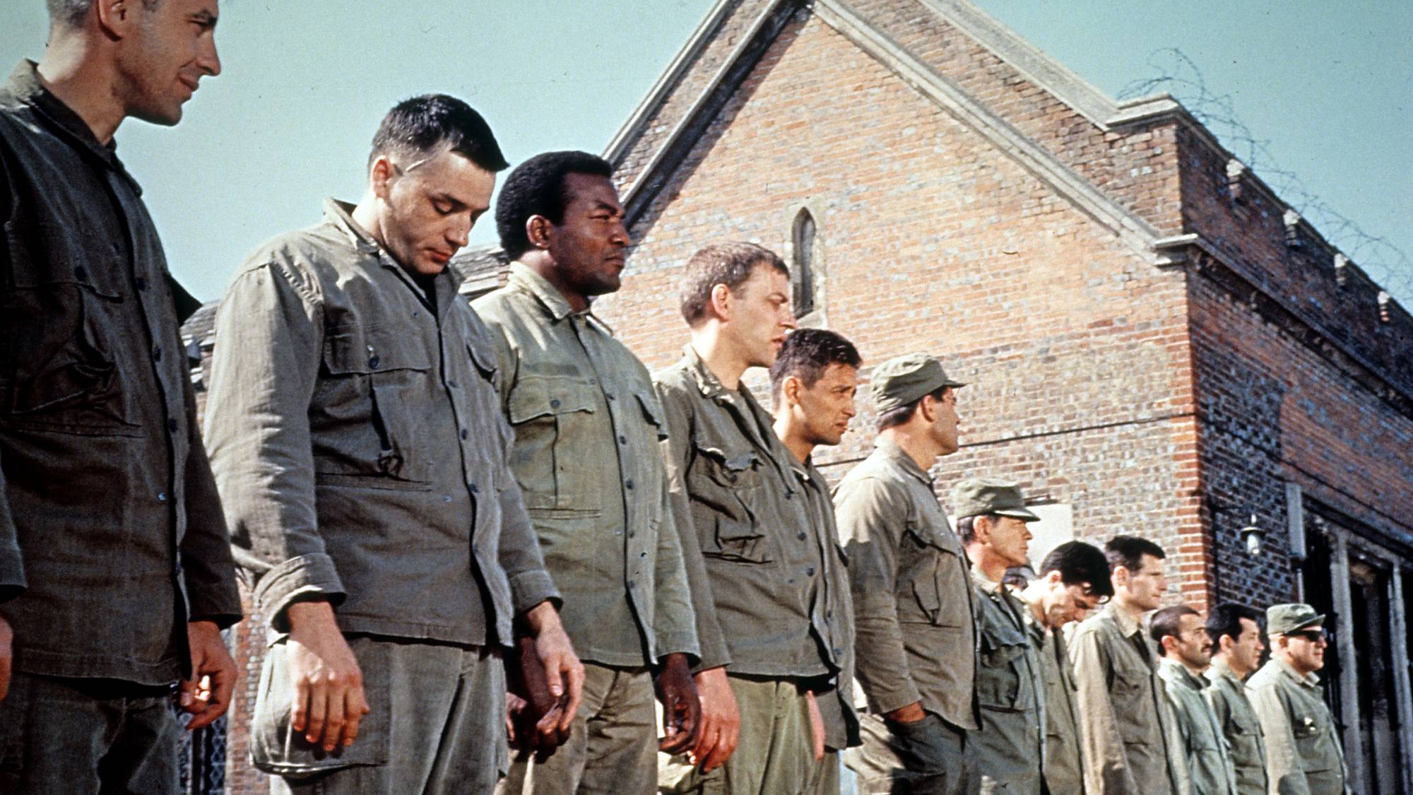 Jim Brown and Donald Sutherland standing in line with other soldiers in a scene from the film 'The Dirty Dozen', 1967. (Photo by Metro-Goldywn-Mayer/Getty Images)