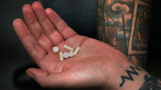 Férfi kézben fájdalom csillapító purilák tetóválással