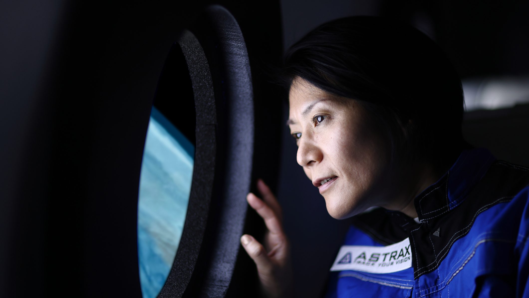 Egy hölgy kinéz egy űrhajó ablakán a földre.