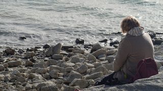 magányos ember üldögél a sziklán