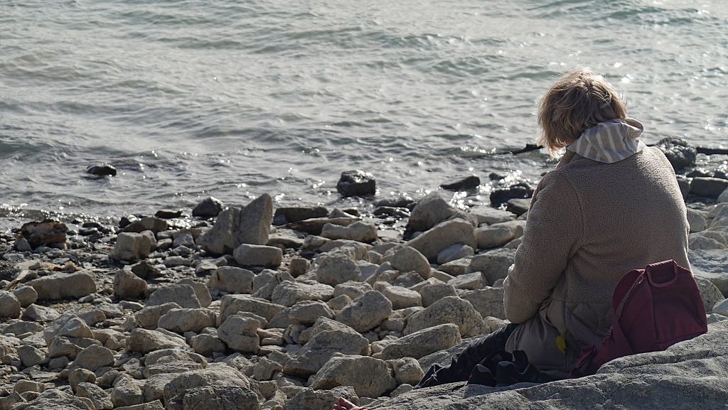 magányos ember üldögél a sziklán