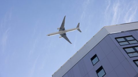 repülőgép repül alatta van egy épület
