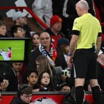 English referee Paul Tierney watches a hair-pulling incident involving Manchester United's Argentinian defender #06 Lisandro Martinez and Leeds United's English striker #09 Dominic Calvert-Lewin on a pitch-side monitor resulting in a red card for Martinez during the English Premier League football match between Manchester United and Leeds United at Old Trafford in Manchester, north west England, on April 13, 2026.