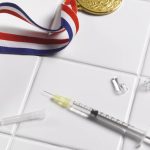 . Medal and syringe on tiled floor - stock photo