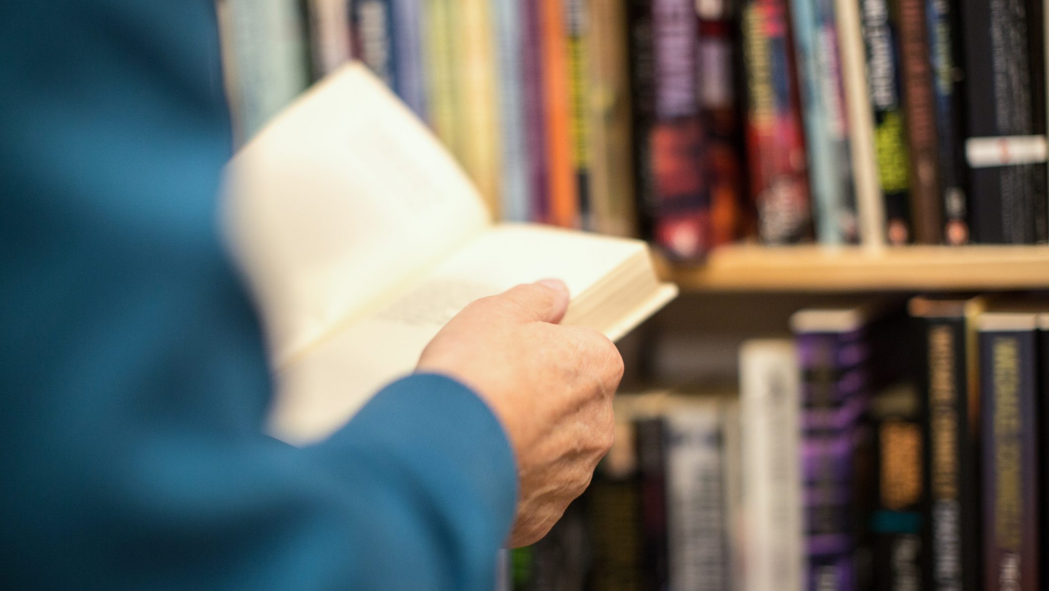 Cropped image of senior male customer holding book while standing in bookstore