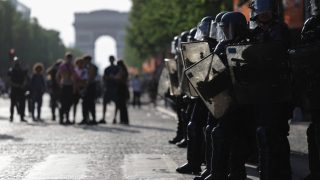 French Republican Security Corps (CRS - Compagnies Republicaines de Securite) Police officers (R) stand by as Paris Saint-Germain's supporters gather on the Champs-Elysees Avenue during the UEFA Champions League final football match between Paris Saint-Germain (PSG) and Arsenal FC played in Budapest, in Paris on May 30, 2026.