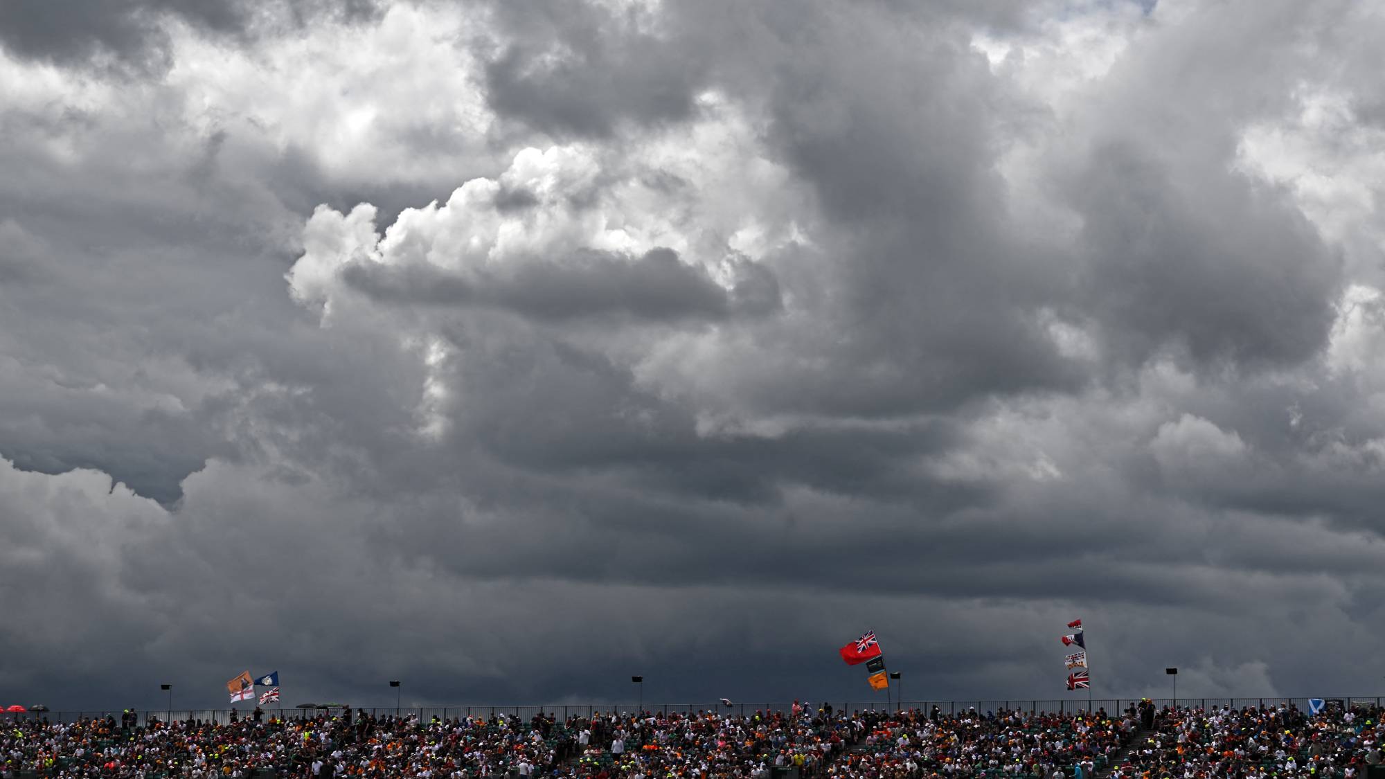 Fans sit in the stands as storm clouds gather in the sky above, ahead of the Formula One British Grand Prix at the Silverstone motor racing circuit in Silverstone, central England on July 3, 2022.