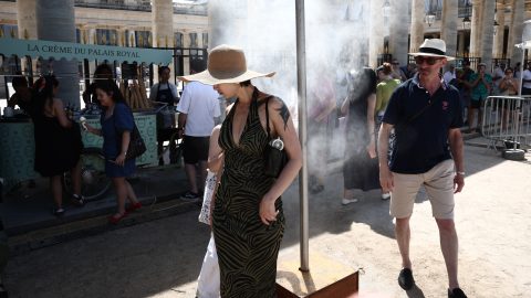 Pedestrians cool off under a mist sprayer installed by Paris City Hall on the 45th edition of the Fete de la Musique (France's national music festival) and during a heatwave in Paris on June 21, 2026. Who will dare to dance in the blazing sun? The Fete de la Musique (France's national music festival) is set to be severely disrupted on June 21, 2026, by the heatwave, particularly in the 35 departments under a red alert – a record number – where alcohol consumption will be banned. The authorities have also urged caution when swimming, following the deaths of four teenagers who drowned on June 20, 2026, in Besancon, the Dordogne and Dunkirk. (Photo by Guillaume BAPTISTE / AFP)