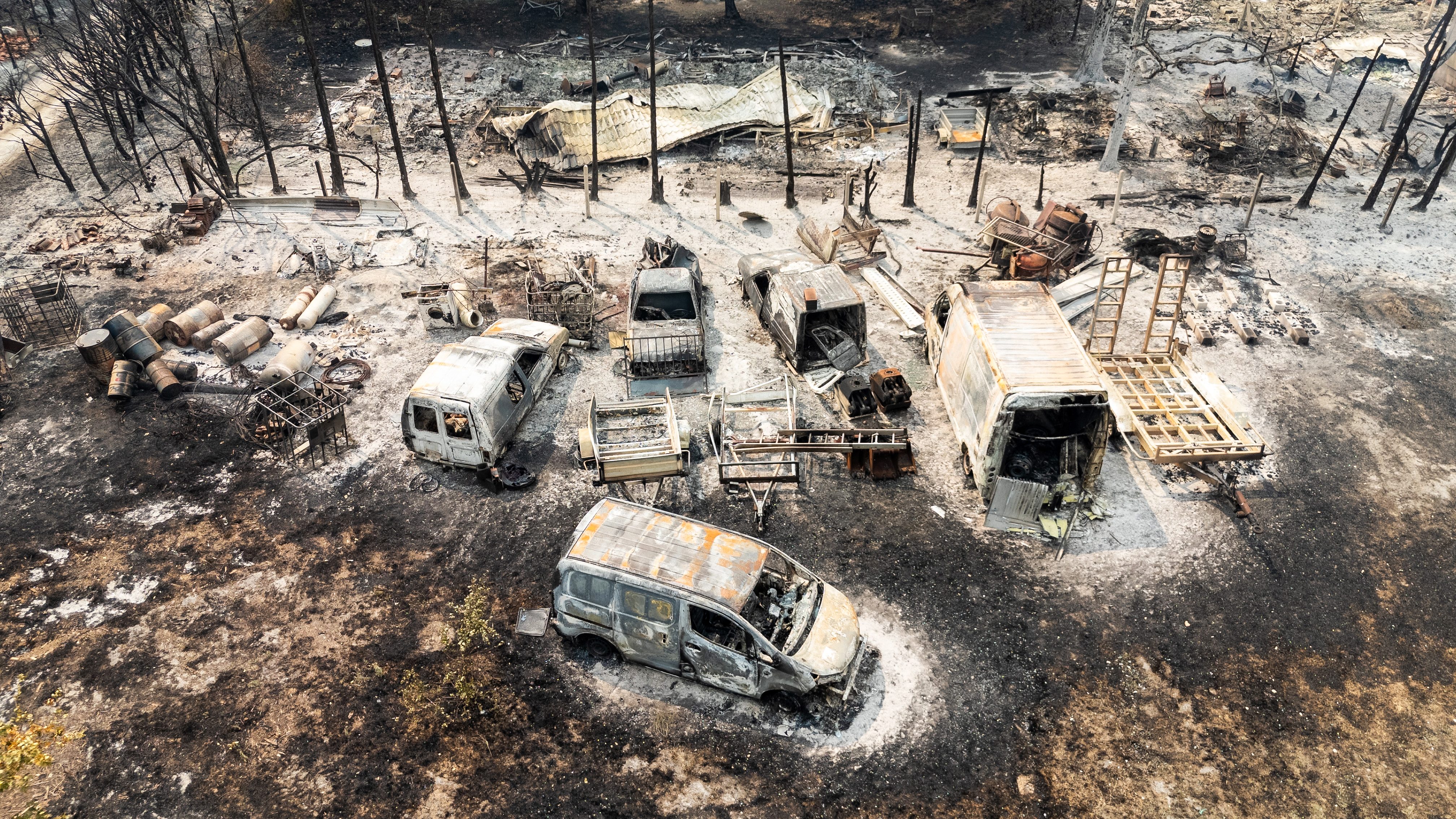 This aerial view shows burnt cars following a wildfire in Le Porge, in the Gironde Department, south-western France on July 25, 2026. The fires, which are on an unprecedented scale and have forced the evacuation of around 200,000 "fire refugees" in Gironde and the Landes, were still not under control on July 25, 2026 and continue to keep firefighters and military personnel on high alert, including an A400M aircraft deployed to tackle the blaze for the first time. (Photo by Florian PLAUCHEUR / AFP)