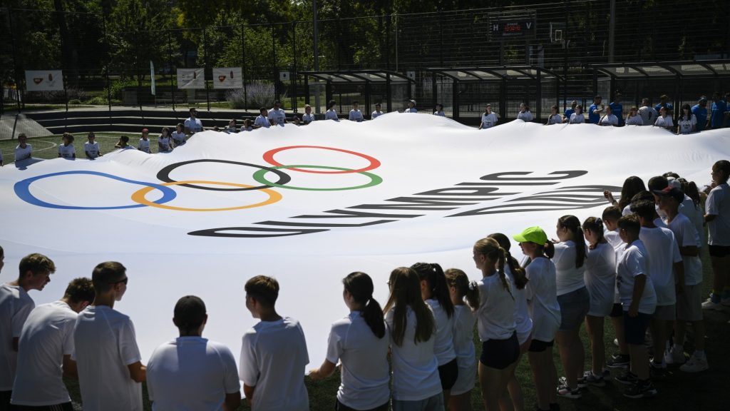 Résztvevők a rendezvény zászlóját feszítik ki az Olimpia Napja alkalmából rendezet családi sportnapon a Városligetben.