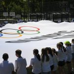 Résztvevők a rendezvény zászlóját feszítik ki az Olimpia Napja alkalmából rendezet családi sportnapon a Városligetben.