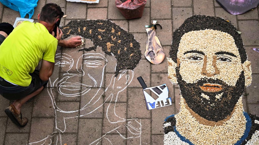 Kosovar artist Alkent Pozhegu works on a mosaic on the ground, made with grain and seeds, and depicting Argentina's forward #10 Lionel Messi (R) and Spain's forward #19 Lamine Yamal, in the town of Gjakova on July 16, 2026. Thousands of kilometres away from New York, where the Argentina and Spain football teams will compete for the World Cup title, in the western city of Gjakova, Alkent Pozhegu has made a mosaic depicting the two forward stars Lionel Messi and Lamine Yamal.