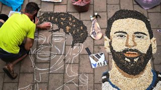 Kosovar artist Alkent Pozhegu works on a mosaic on the ground, made with grain and seeds, and depicting Argentina's forward #10 Lionel Messi (R) and Spain's forward #19 Lamine Yamal, in the town of Gjakova on July 16, 2026. Thousands of kilometres away from New York, where the Argentina and Spain football teams will compete for the World Cup title, in the western city of Gjakova, Alkent Pozhegu has made a mosaic depicting the two forward stars Lionel Messi and Lamine Yamal.