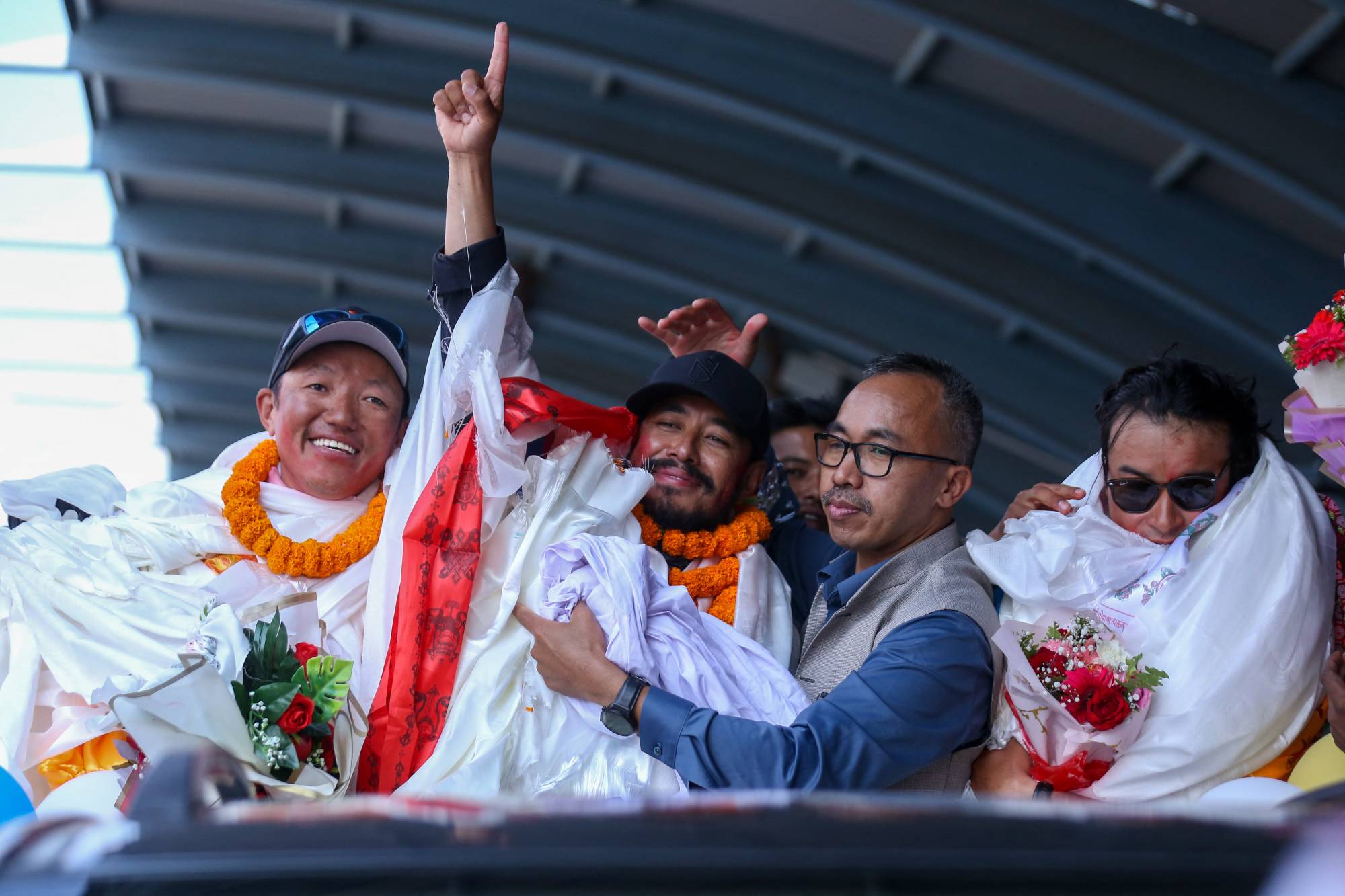 Record-setting climber Nirmal Purja, also known as Nimsdai, signals victory as he arrives back in Kathmandu, Nepal, on October 14, 2024, after completing the summit of 14 peaks towering above 8000 meters without oxygen. On May 7, 2022, climber Nims begins this campaign by summiting Kanchenjunga without using supplemental oxygen. On May 27 of the same year, he ascends Everest, followed by Lhotse on May 28, Makalu, Cho Oyu, Dhaulagiri, Annapurna, Manaslu, Nanga Parbat, Gasherbrum, Broad Peak, and finally Shishapangma. Out of the 14 tallest peaks, eight are located in Nepal, while the others are in Pakistan and China. (Photo by Subaas Shrestha/NurPhoto)