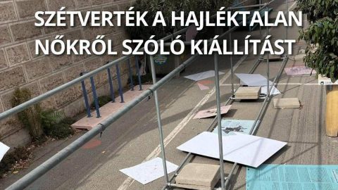 A street protest installation with scattered posters and metal barriers, overlayed by large Hungarian text about vandalized exhibit on homeless women.