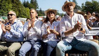 Group of people in white shirts and straw hats clapping at an outdoor event.