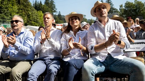 Group of people in white shirts and straw hats clapping at an outdoor event.