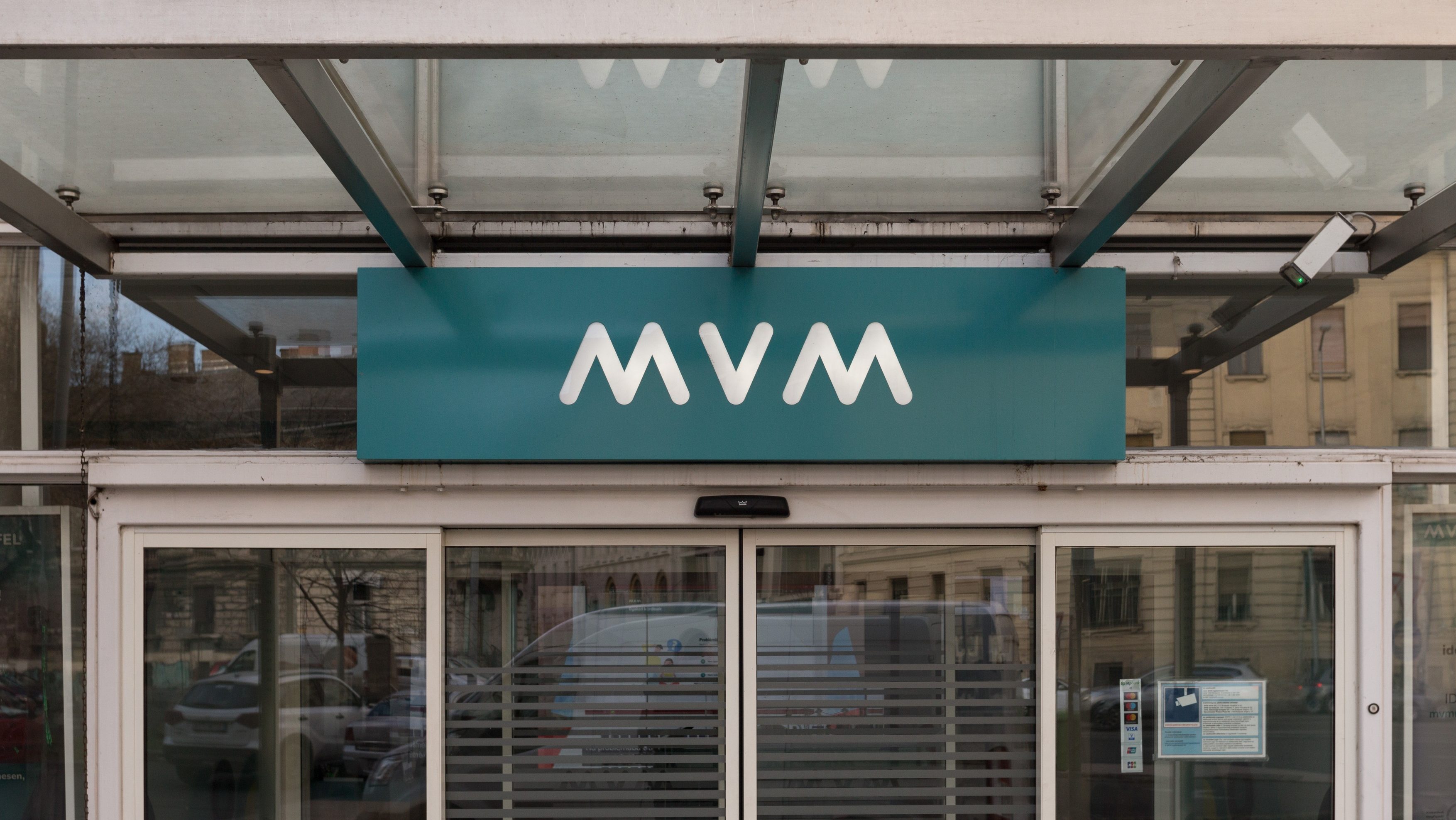 Teal storefront sign with white MVV logo above glass doors.