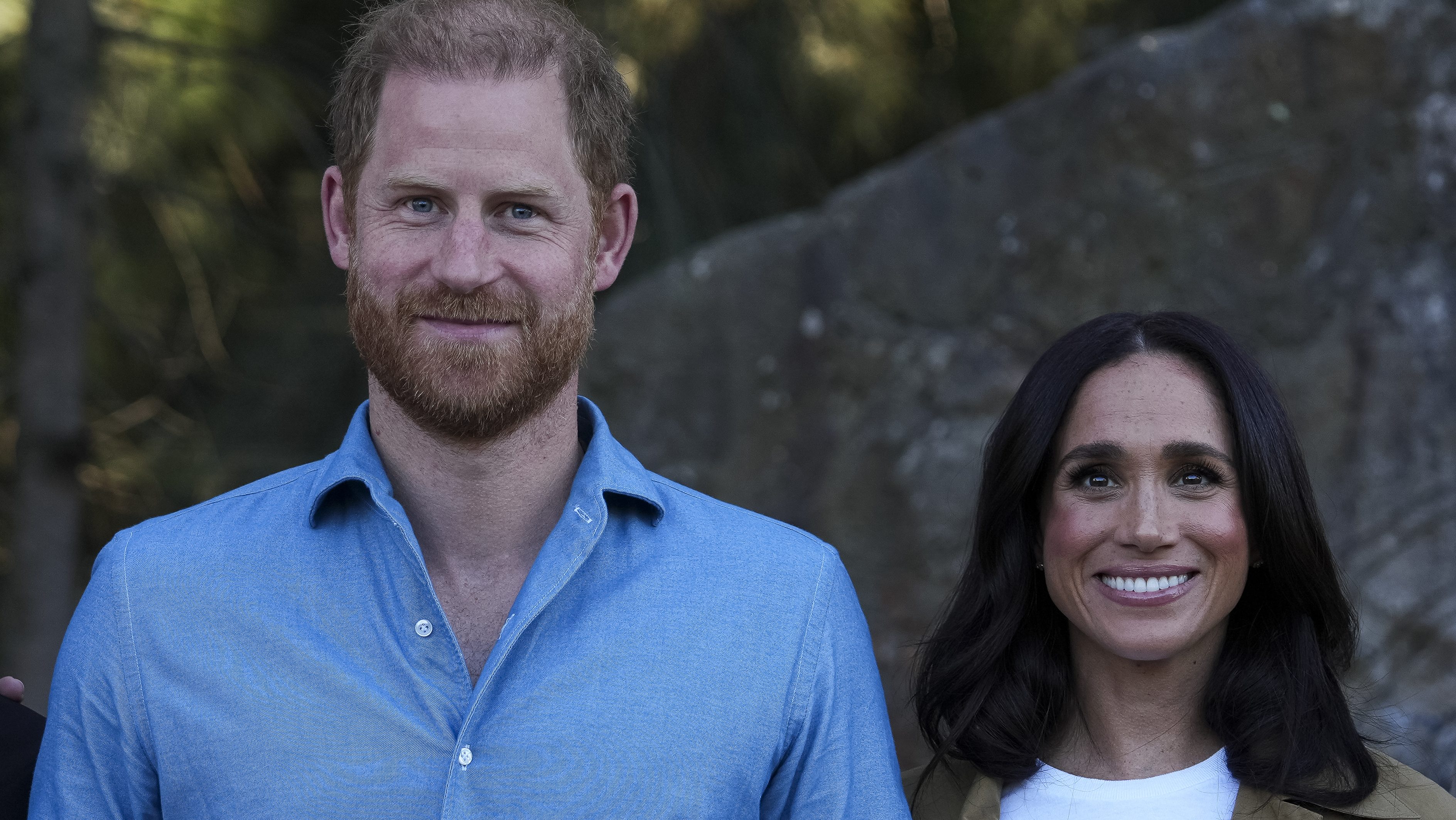 Smiling man with a blue shirt standing outdoors beside a woman with dark hair and a white top.