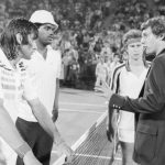 (Original Caption) John McEnroe (background) looks on as an unidentified official talks to Ilie Nastase about his show of temper and tantrum during his US Open meeting with McEnroe. The man next to Nastase is unidentified.