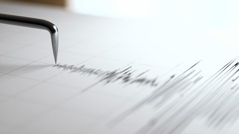 Close-up of a shiny pen nib touching graph paper as it writes.