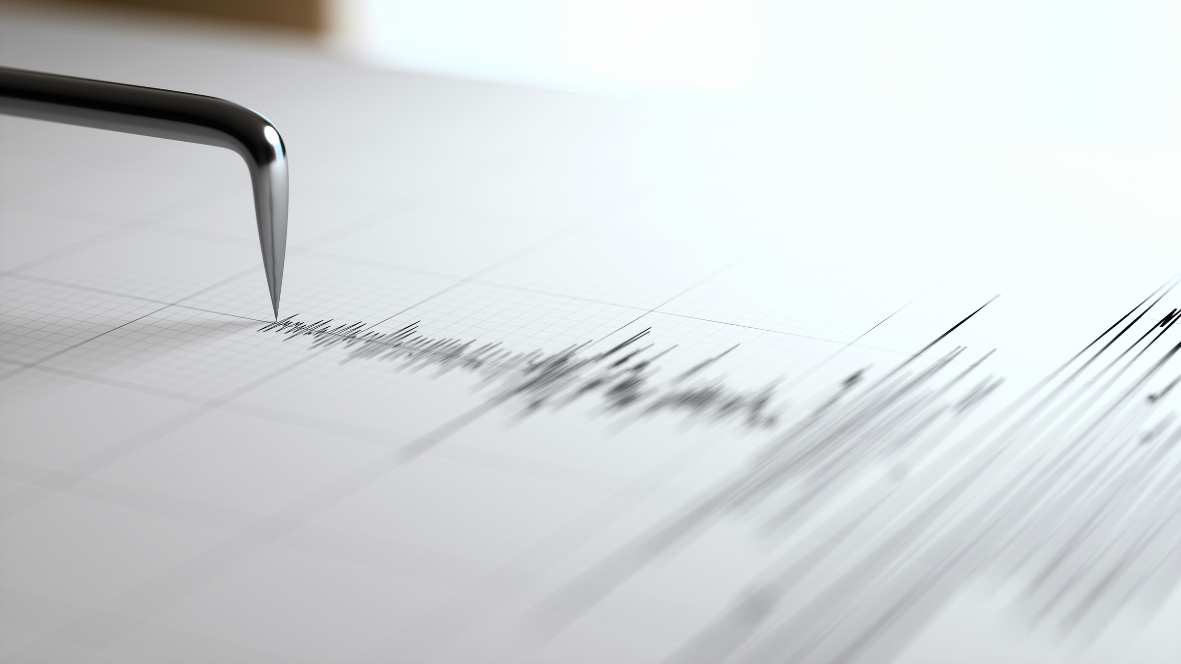 Close-up of a shiny pen nib touching graph paper as it writes.