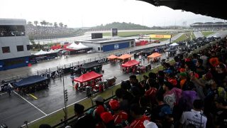Teams gather around the cars as the start of the race has been delayed due to heave rain at the Formula One Bahrain Grand Prix in Sepang on October 4, 2026.
