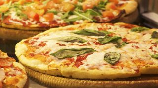 Large cheese pizza topped with fresh basil leaves on a golden crust.