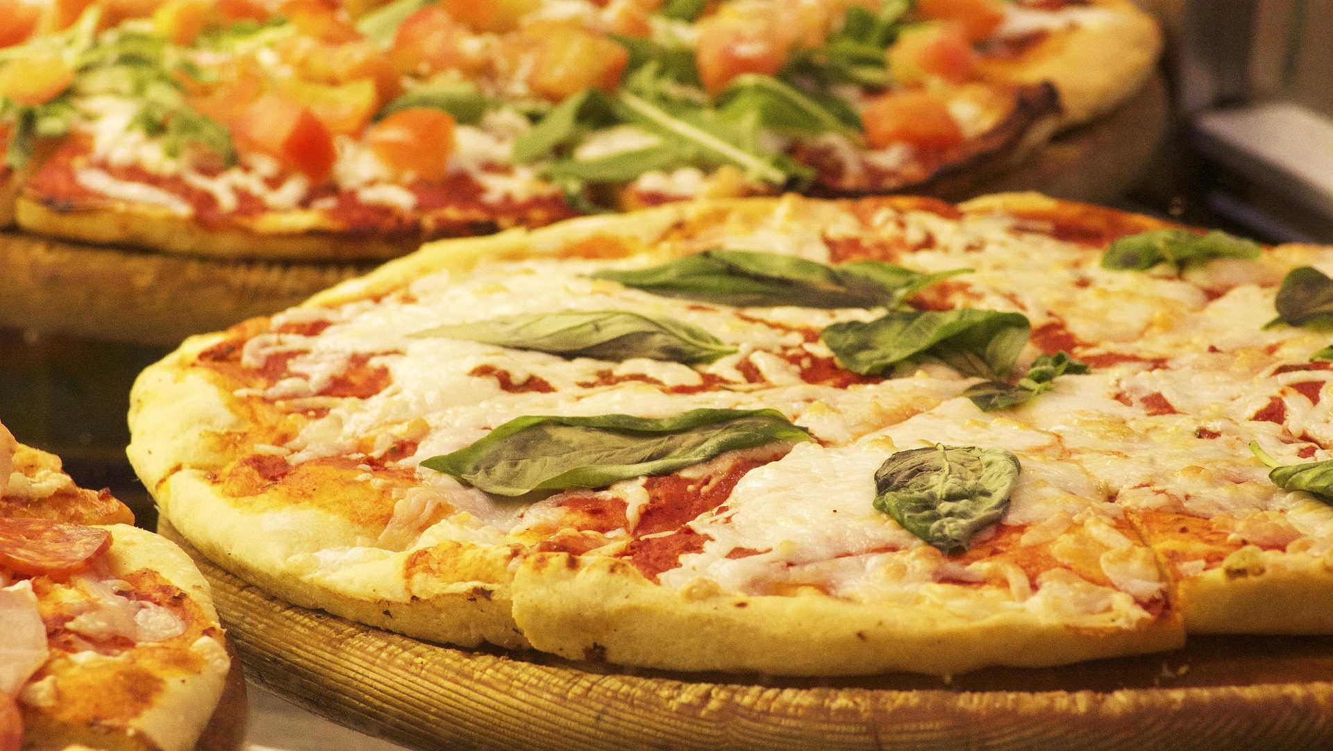 Large cheese pizza topped with fresh basil leaves on a golden crust.