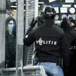 A Genk szurkolójával farkasszemet néző rohamrendőr.