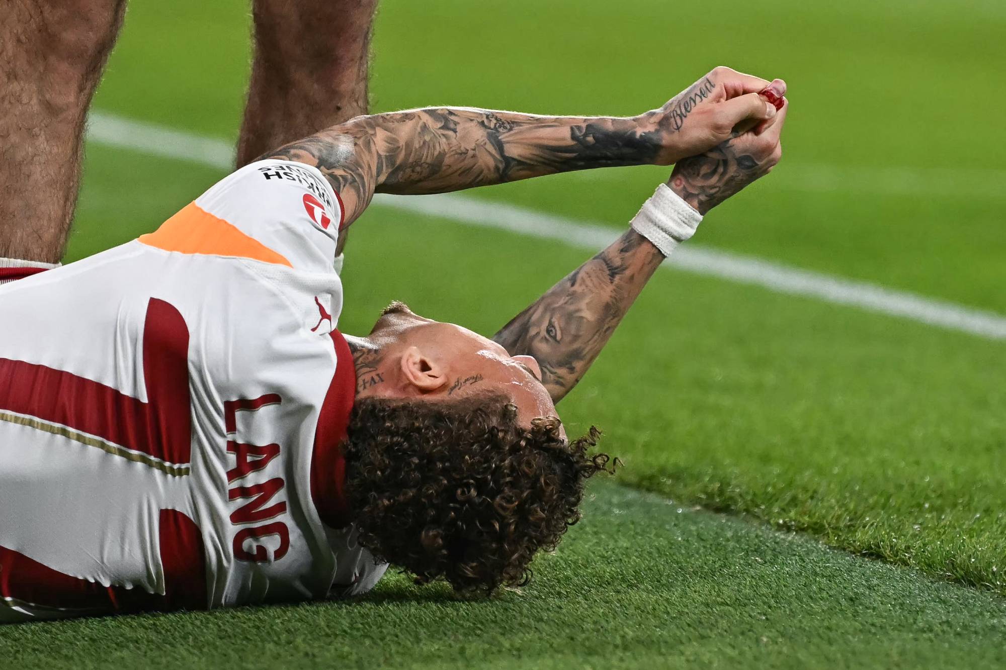 Galatasaray's Dutch forward #77 Noa Lang reacts on the floor after cutting his thumb during the UEFA Champions League, round of 16 second leg football match between Liverpool and Galatasaray at Anfield in Liverpool, north-west England on March 18, 2026.