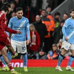 Liverpool's Hungarian midfielder #08 Dominik Szoboszlai (front L) scores from a free kick for his team's first goal during the English Premier League football match between Liverpool and Manchester City at Anfield in Liverpool, north west England on February 8, 2026.
